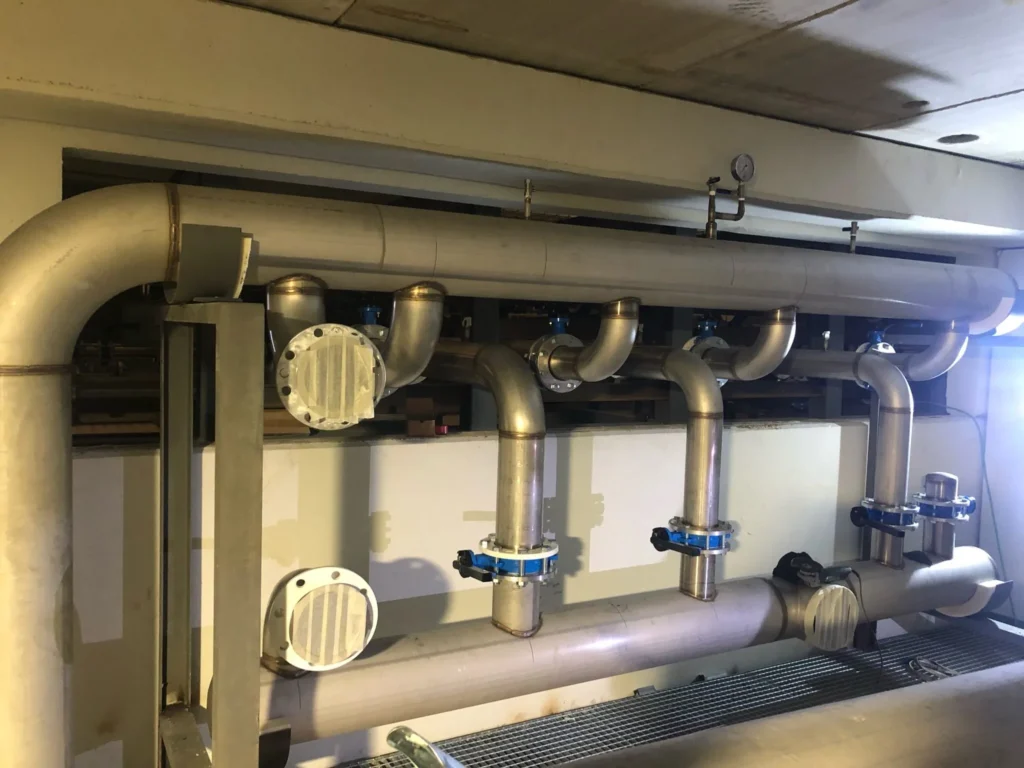 Colector de tubería de acero inoxidable con derivaciones y acoplamientos instalado en sala técnica