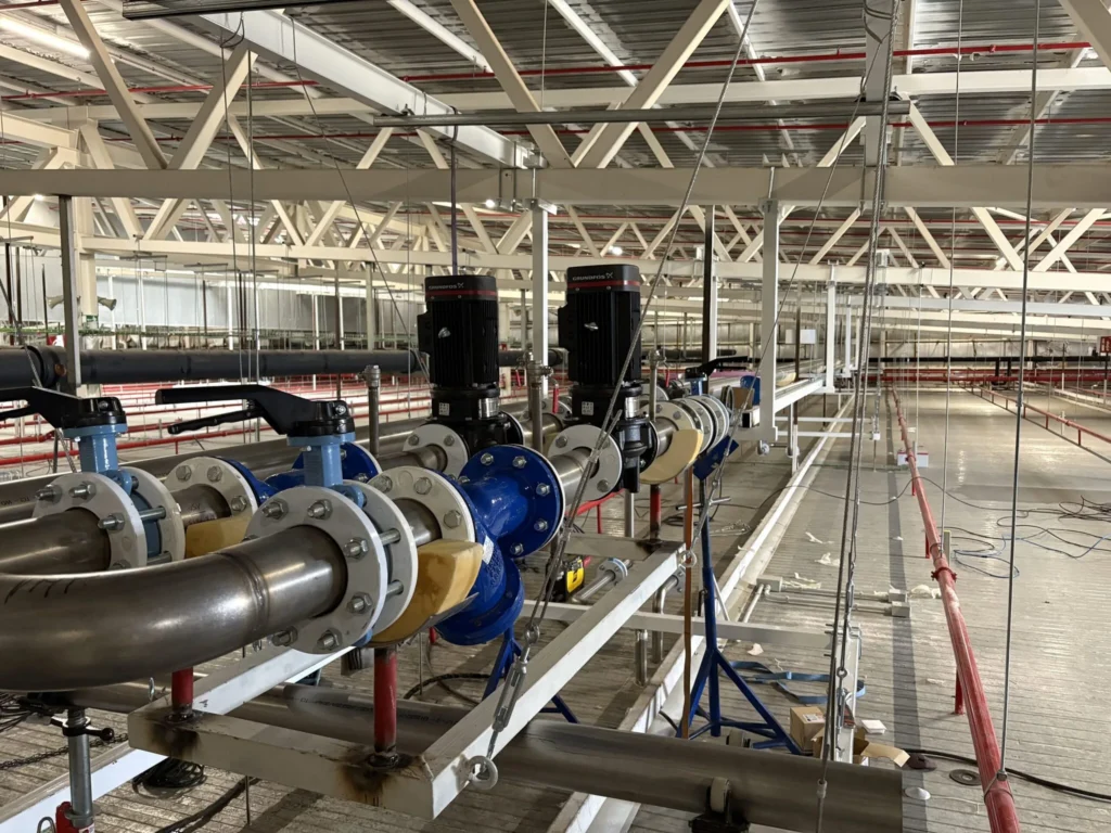Línea de tubería con válvulas de mariposa y bombas verticales instalada en nave industrial