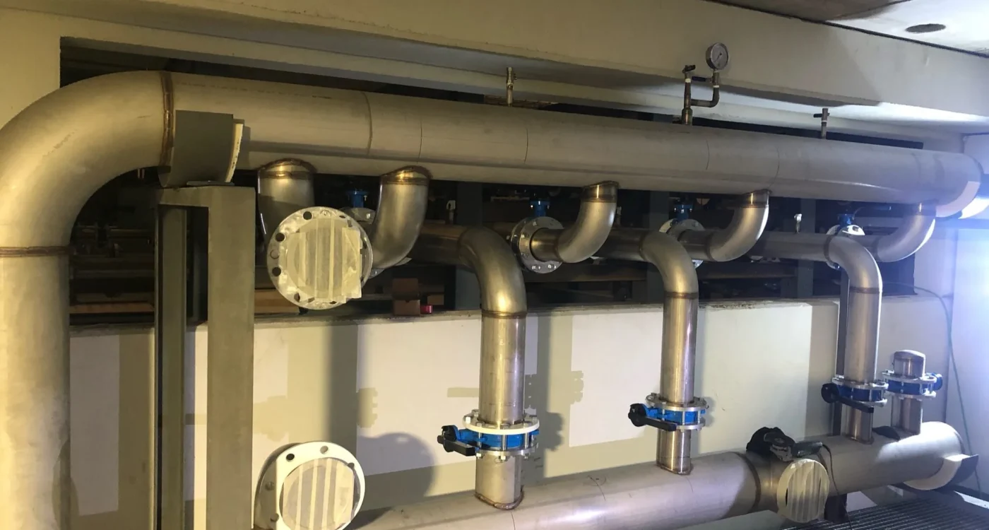 Colector de tubería de acero inoxidable con derivaciones y acoplamientos instalado en sala técnica