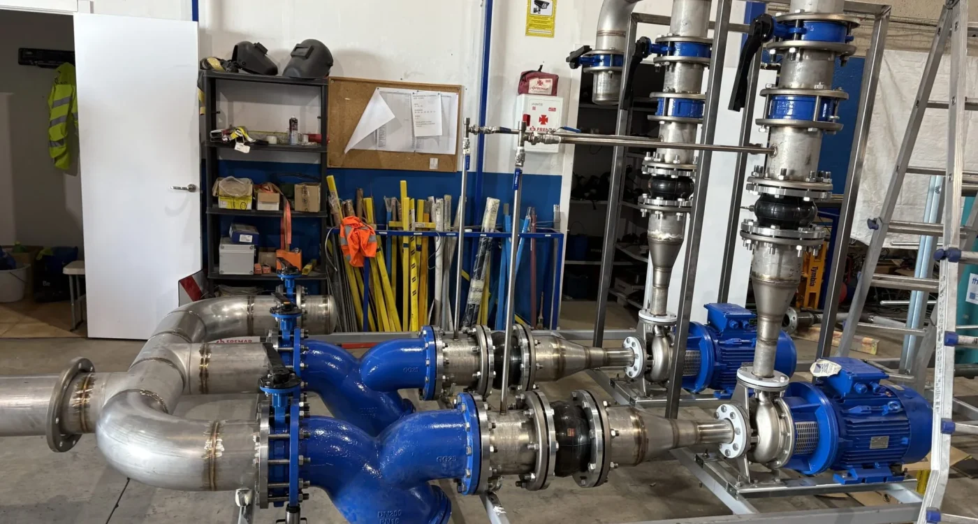 Skid prefabricado en taller con bombas azules, motores y tubería de acero inoxidable sobre bastidor galvanizado